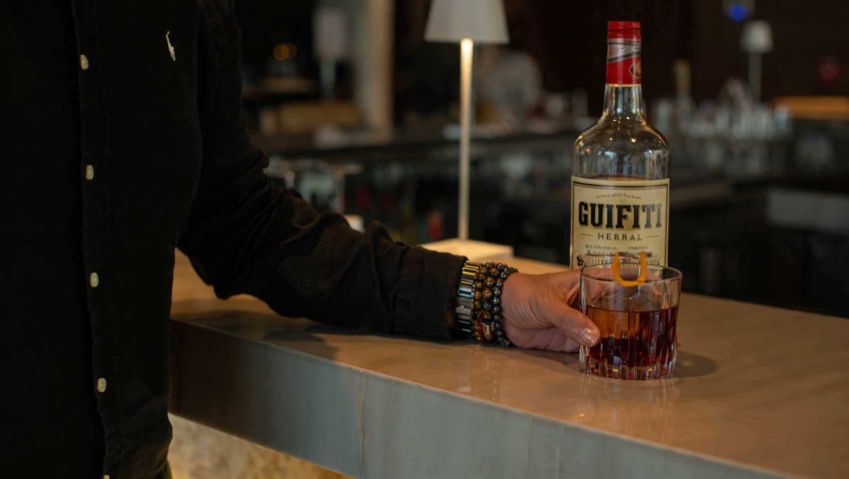 Person with bottle of Guifity standing at the bar