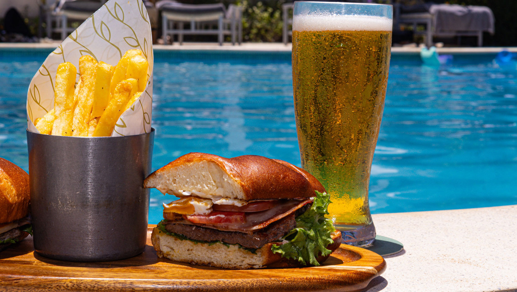 Sandwich, fries, and beer in front of Sea Cat pool