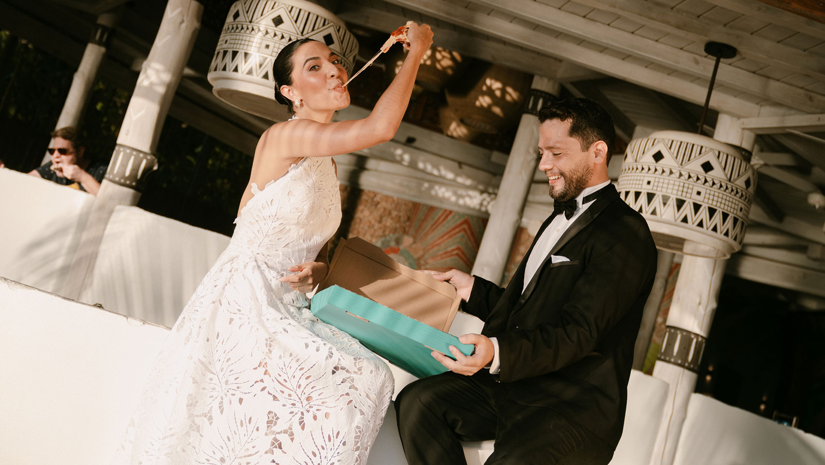 Bride and groom eat pizza on the bar at Kimpton Grand Roatan