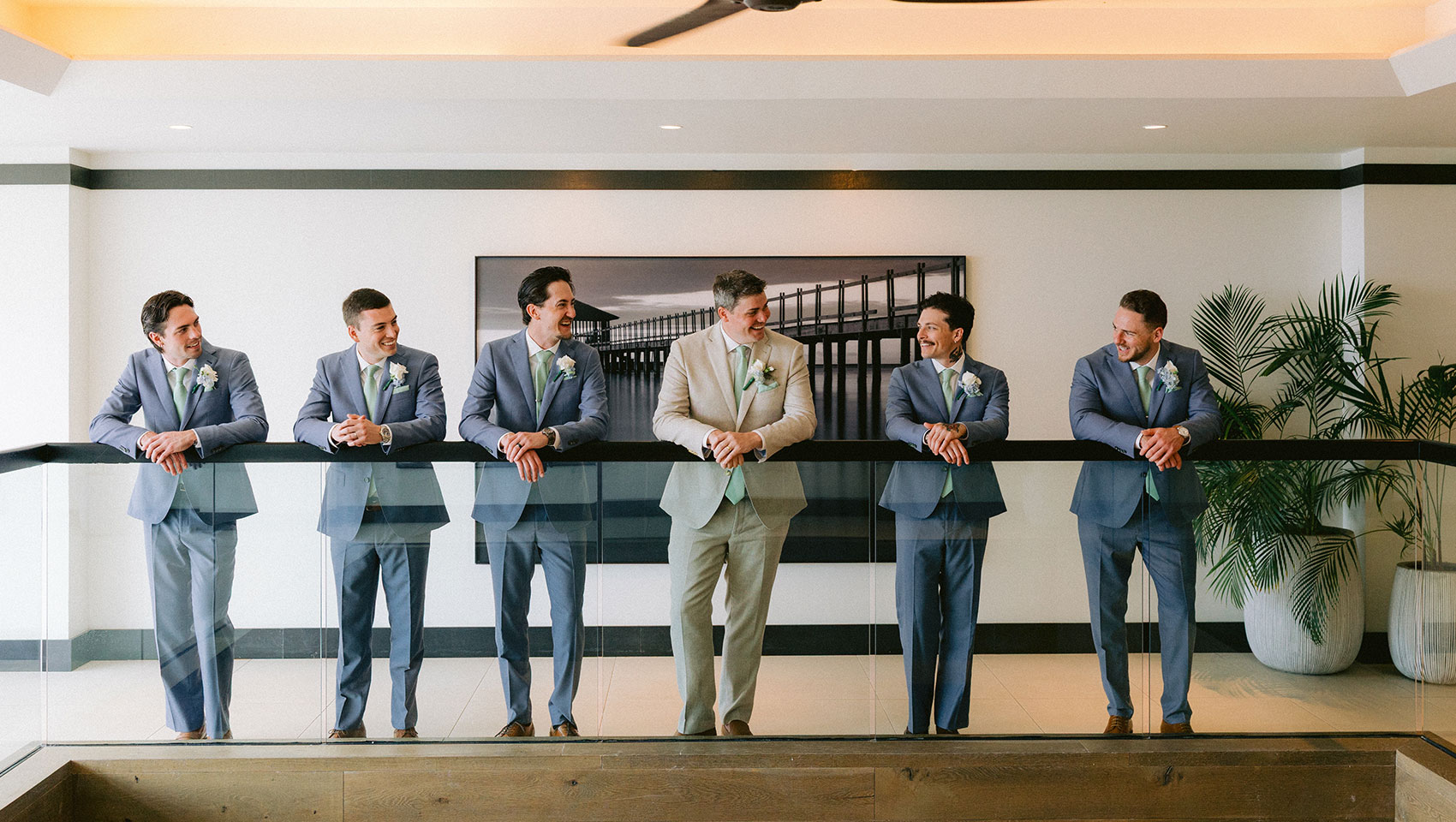groomsmen in matching suits lean on banister at Kimpton Grand Roatan