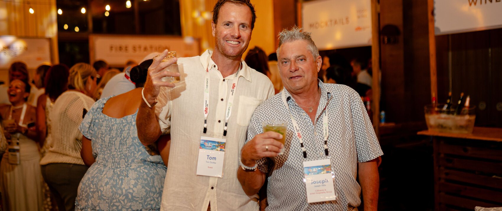 two male guests at the Grand Roatan Beer festival hold up their beers for the camera